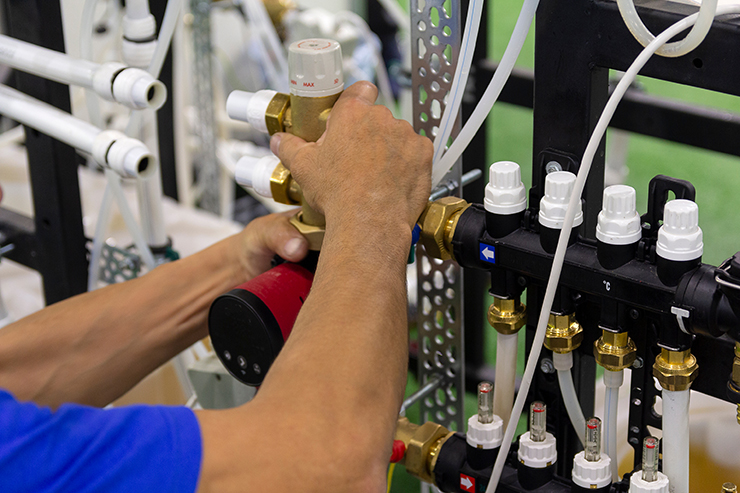 Picture of a tradesperson adjusting some heating pipes for an underfloor heating installation