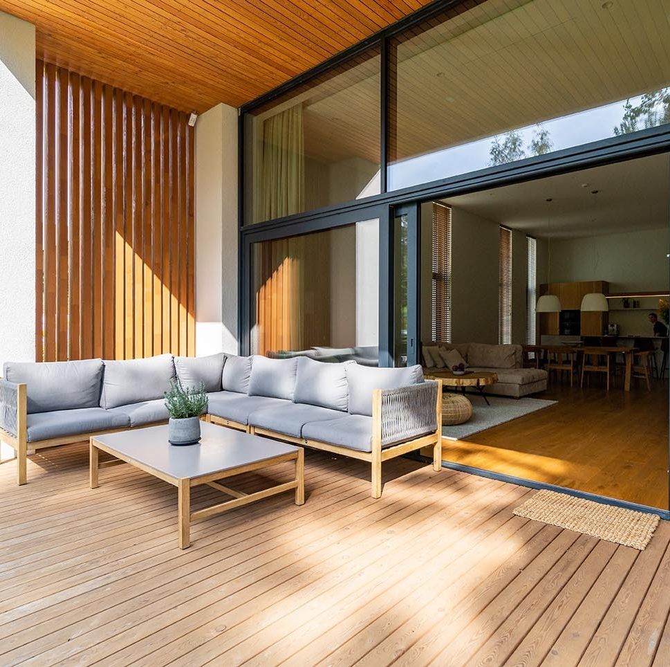 wooden patio connected to a private building, with seating area and cozy lounge zone, open window with entrance to the house