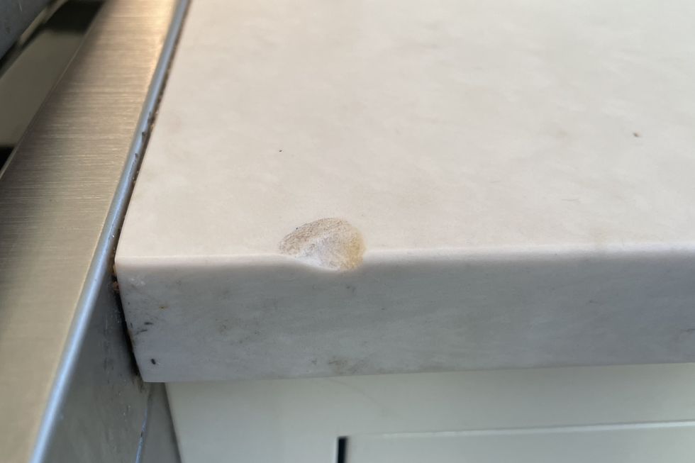 a quartz countertop with a chip in its edge, likely caused by a heavy cast iron pan