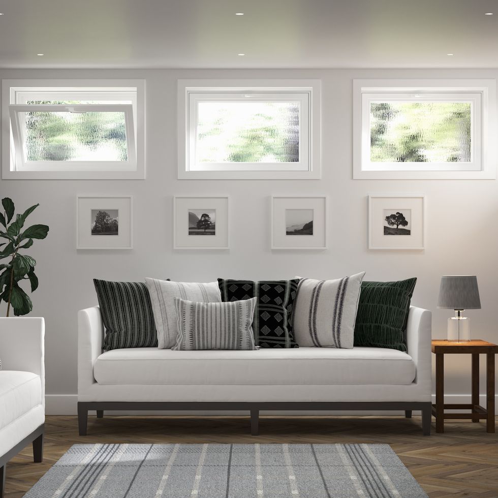 natural light streams into a basement living area through a trio of hopper windows