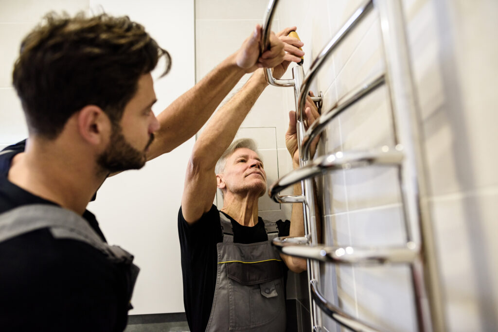 Picture of two plumbers working together to install a radiator 