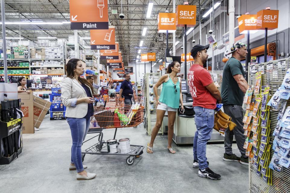 People stand in Home Depot self serve checkout lines.