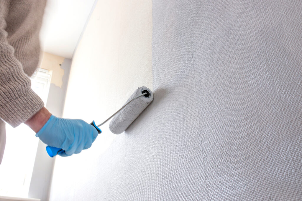 Picture of a paint roller being used to apply grey paint to wall