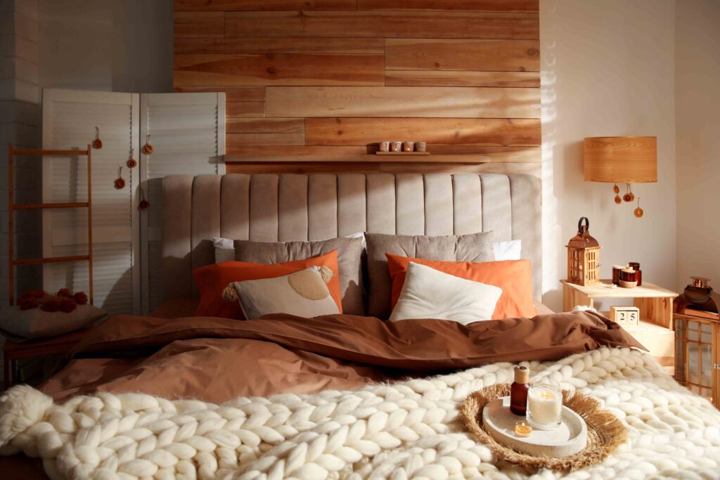 Picture of a bedroom with rust coloured bed sheets on ed and brown panelboard